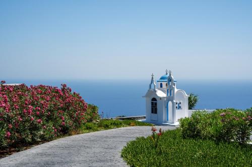 a road leading to a white chapel with flowers at Cresanto Luxury Suites in Imerovigli