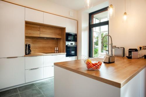 une cuisine avec des armoires blanches et un comptoir en bois dans l'établissement Belle paimpolaise à 100m du port, à Paimpol