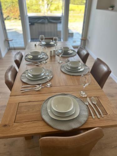 a wooden table with plates and silverware on it at Cosy countryside cottage in Aberystwyth