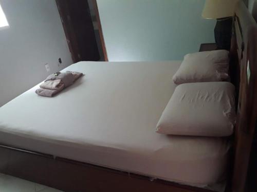 a bed with white sheets and pillows on it at casa cachoeira in Brasilia
