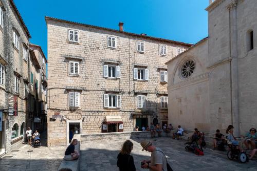 a group of people standing outside of a large brick building at Apartment Centar Trogir in Trogir