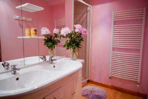 a bathroom with pink walls and a sink with flowers in vases at la margeride in Le Malzieu Forain