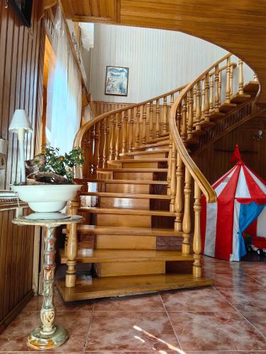 a wooden spiral staircase in a house with a table at Guest House Metreveli Street 19 in Khashuri