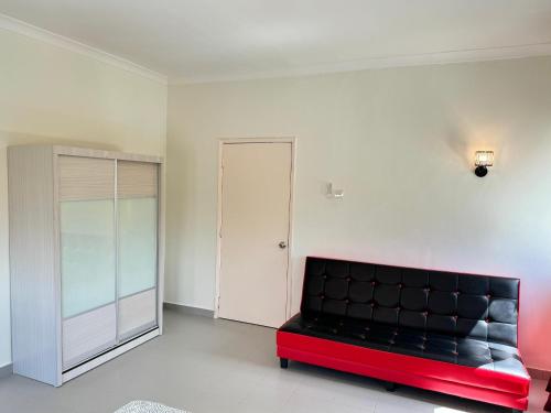 a black and red couch in a room with a door at Penthouse Desaru Beach 5G Wifi Netflix Pool View in Bandar Penawar