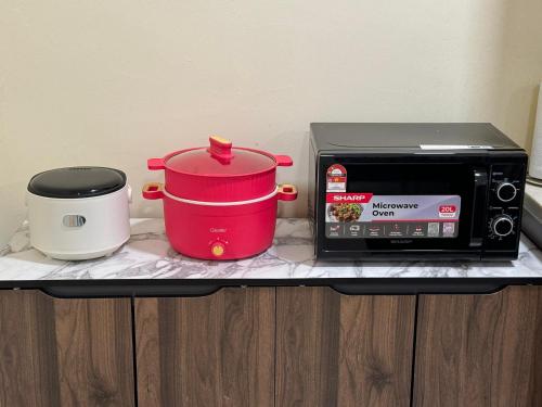 a microwave and a toaster oven with two pots and pans at Penthouse Desaru Beach 5G Wifi Netflix Pool View in Bandar Penawar
