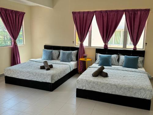 two beds in a bedroom with purple curtains at Penthouse Desaru Beach 5G Wifi Netflix Pool View in Bandar Penawar