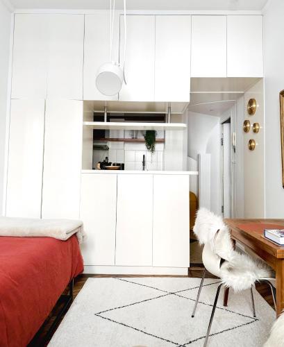 - une cuisine blanche avec des placards blancs et une table dans l'établissement Studio climatisé pour 1 ou 2 personnes au 109 avenue Mozart Paris 16, à Paris