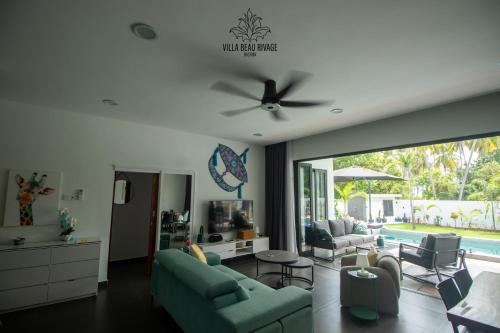 a living room with a couch and a ceiling fan at Villa Beau Rivage in Bachok