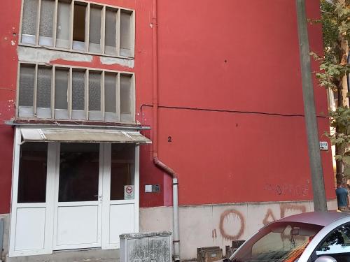 czerwony budynek z białymi drzwiami na ulicy w obiekcie Lucia apartman w mieście Kaposvár