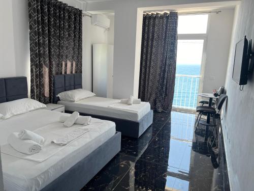 a hotel room with two beds and a window at Redi's Seaview Apartments in Sarandë