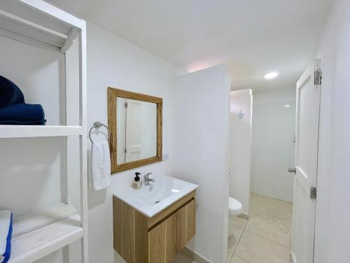 a white bathroom with a sink and a mirror at Hotel Carey Beach Baru in Baru