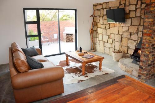 a living room with a couch and a table and a fireplace at RuaWilla Guest Cottage in Lutzville