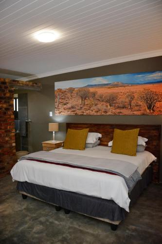 a bedroom with a large bed with a painting on the wall at RuaWilla Guest Cottage in Lutzville
