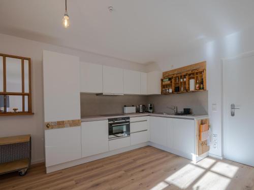 a kitchen with white cabinets and a wooden floor at Lindenhof Michaelis - Urlaub auf dem historischen Gutshof in Liebstadt