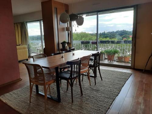 une table de salle à manger avec des chaises et une grande fenêtre dans l'établissement Chambre chez Casa Créteil, à Créteil