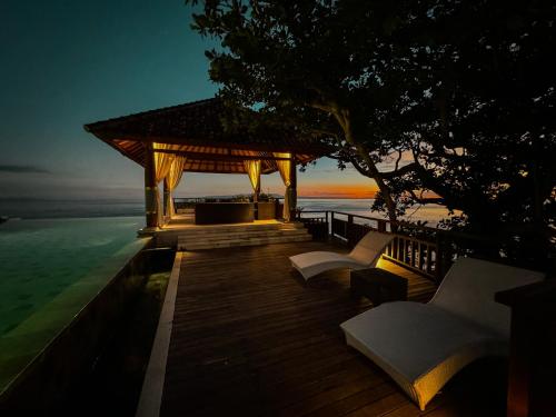 a gazebo with chairs and the ocean at night at Raaga Samudra Villa in Padangbai