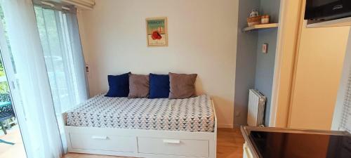 ein kleines Schlafzimmer mit einem Bett mit blauen Kissen in der Unterkunft charmant studio plage et marché à pied in Pornichet