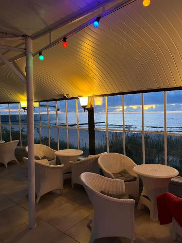 a patio with chairs and tables and a view of the ocean at BAłTYK NAD MORZEM-PRZY PLAŻY in Niechorze