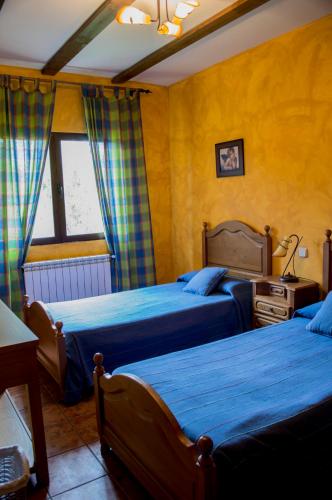 a bedroom with two beds and a table and a window at Apartamentos Rurales Alvado in Tamajón
