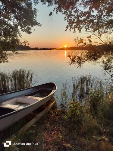 a boat sitting on the shore of a lake at sunset at Retro House in Savonlinna