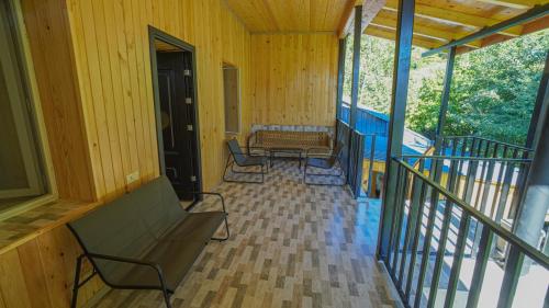 a porch with two chairs and a bench on it at Givi Kakhiani's Svaneti Guesthouse in Zhabeshi