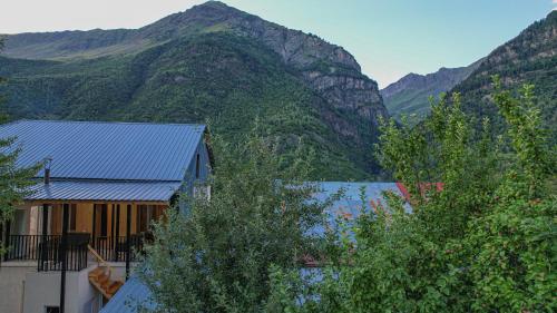 a house in front of a mountain with trees at Givi Kakhiani's Svaneti Guesthouse in Zhabeshi