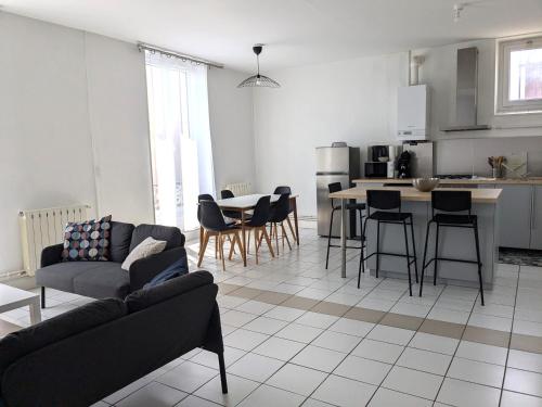un salon avec un canapé et une cuisine dans l'établissement Grand appartement lumieux avec parquet, à Nevers