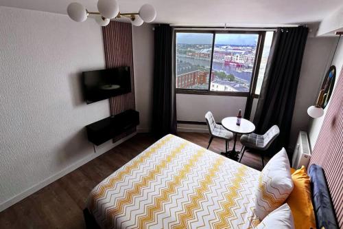 a bedroom with a bed and a table and a window at Studio Les Embruns in Dunkerque