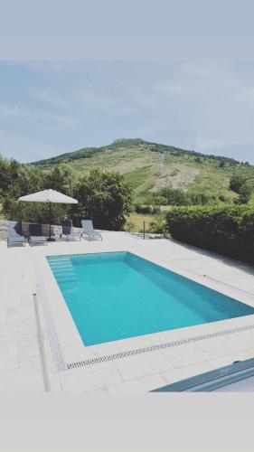 a swimming pool with two chairs and an umbrella at Casa rural la castañona in Buiza