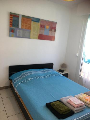 une chambre avec un lit bleu avec des serviettes dessus dans l'établissement Appartement 2 étoiles entre les Maures et Méditerranée, à La Londe-les-Maures