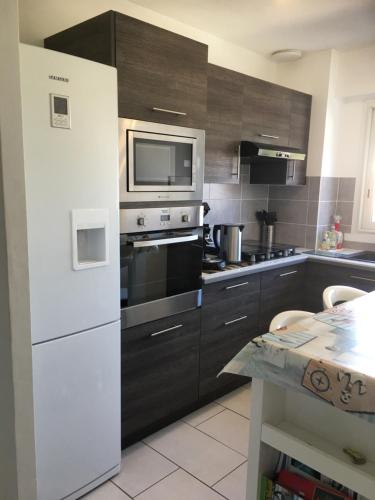 La cuisine est équipée d'un réfrigérateur blanc et d'un four micro-ondes. dans l'établissement Appartement 2 étoiles entre les Maures et Méditerranée, à La Londe-les-Maures