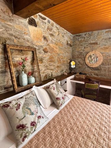 a bedroom with a bed in a stone wall at Casa Da Oliveira in Pedrógão Grande