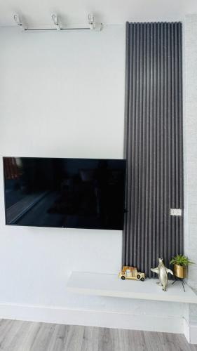 a television on a white wall with a white shelf at Vela House Hatyai in Hat Yai