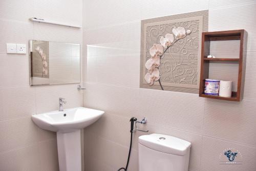 a white bathroom with a sink and a toilet at The Change Hotel in Kandy