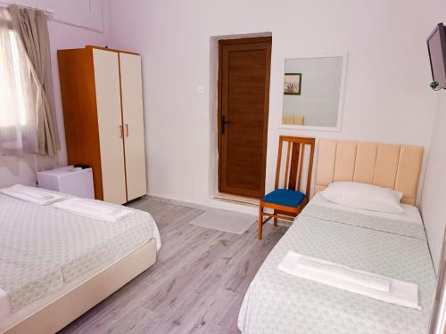 a bedroom with two beds and a chair and a door at Kalipso motel in Çeşme