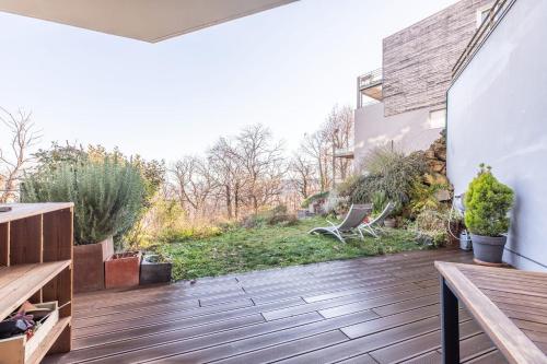 a patio with a wooden deck with a bench at Horizon Feng Shui - jardin, terrasse et vue in Ceyrat