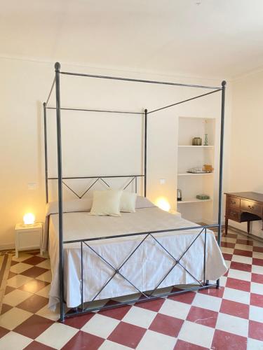 a bedroom with a canopy bed with a checkered floor at La Dimora di Pindaro in Colledimacine