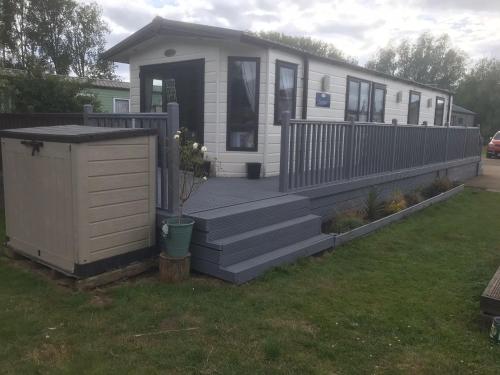 a small house with a porch and a yard at Beautiful 2 bedroom caravan on Billing Aquadrome in Northampton
