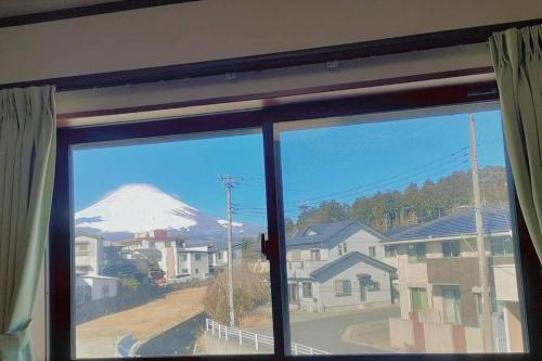 a view of a snow covered mountain from a window at 駅近4分 富士山を眺める和風宿 in Gotemba