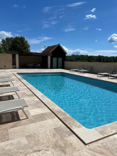 une piscine avec des chaises et un bâtiment dans l'établissement Village des Éléments, à Naussannes
