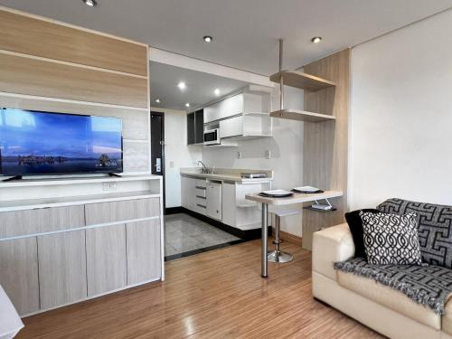 a living room with a couch and a tv and a kitchen at Lake Side Resort Flat Beira Lago 5 minutos do centro de Brasília in Brasília