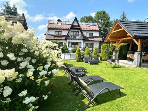 a group of chairs sitting in the grass in front of a house at DW Basia pokoje i apartament in Białka Tatrzanska