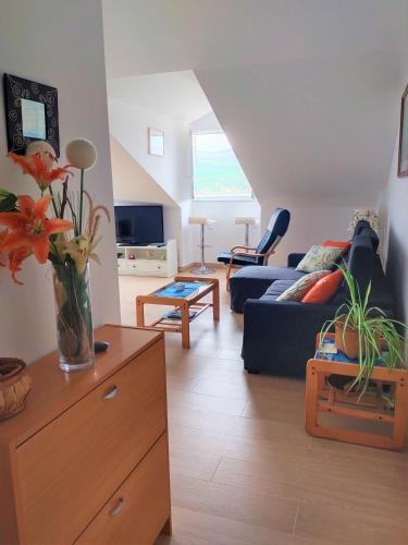 a living room with a vase of flowers on a dresser at Ático Agarimos do Mar in Corcubión