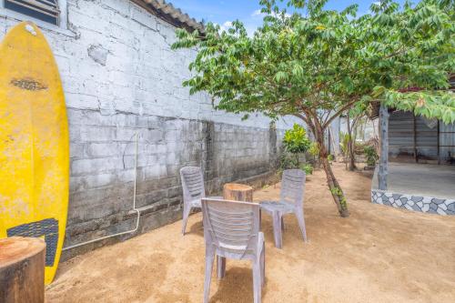 a table and chairs and a surfboard next to a wall at The Baysura Arugambay in Arugam Bay