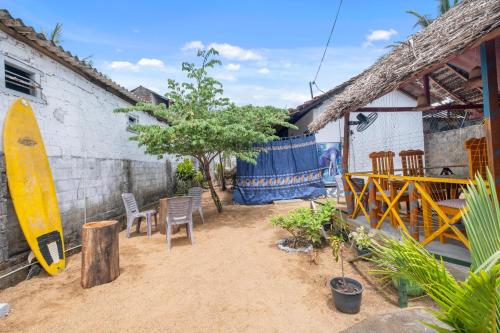 a patio with chairs and a surfboard next to a building at The Baysura Arugambay in Arugam Bay