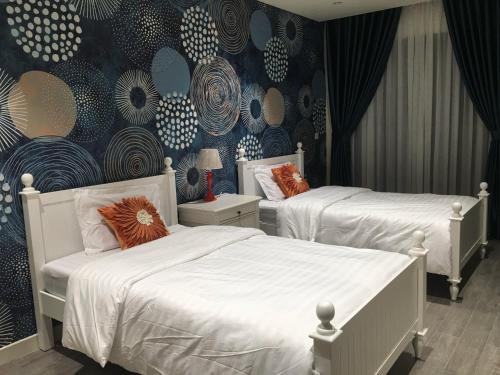 a bedroom with two beds and a blue and white wall at Wonderland Hồ Tràm - Mocha Viva in Ho Tram