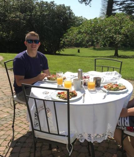 un homme assis à une table avec des assiettes de nourriture dans l'établissement Drumee Lodge boutique B and B, Newcastle, County Down, à Newcastle