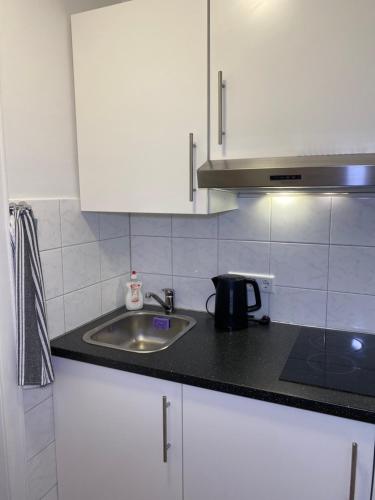 a kitchen with white cabinets and a sink at Downtown Residence Düsseldorf in Düsseldorf