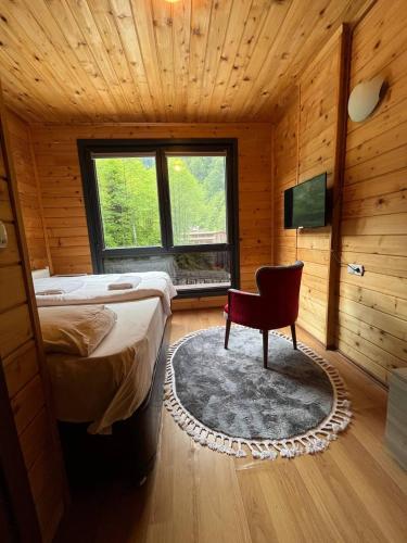 a bedroom with a bed and a chair and a television at Ayder Paradise Otel in Ayder Yaylasi