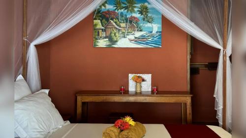 a bedroom with a bed and a table with flowers on it at VERONIKA Resort Nosy Komba in Nosy Komba